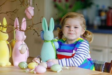 Cute little toddler girl decorating tree and bunny with...