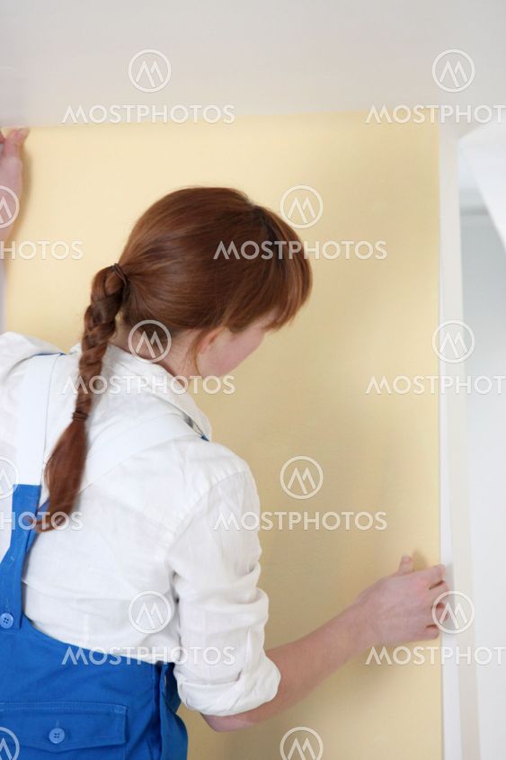 Woman hanging wallpaper