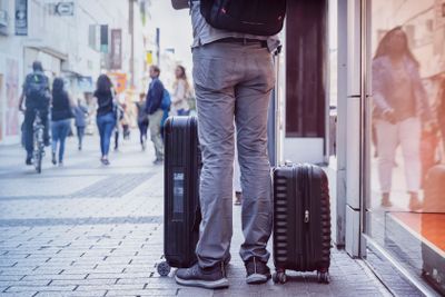 Unrecognizable young man traveling with suitcases, city...
