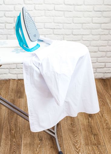 Iron on ironing board on light home interior background