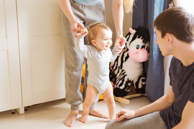 Happy family smiling as baby takes first steps