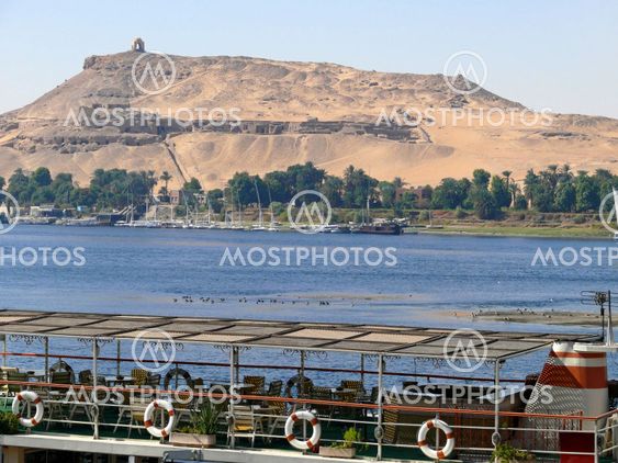 Pier on the bank of the Nile in Aswan, on a background of ancient sites in Egypt.
