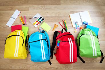 Colourful children schoolbags on wooden floor