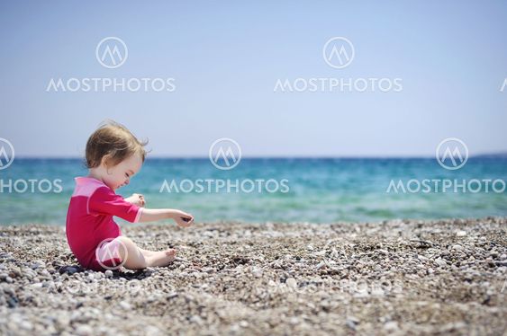 Cute girl playing on pebble beach