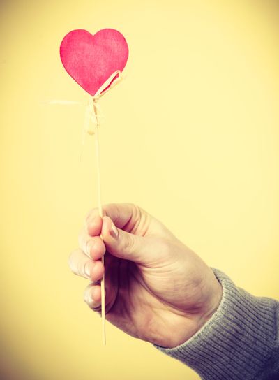 Person holding heart on stick.