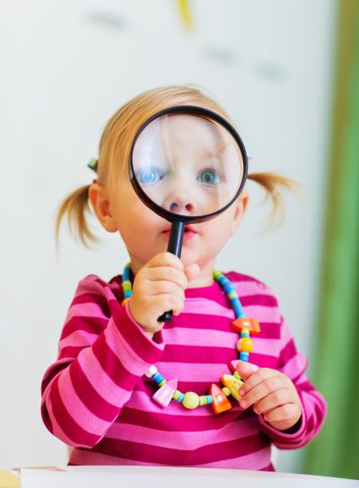 Toddler girl looking through magnifier