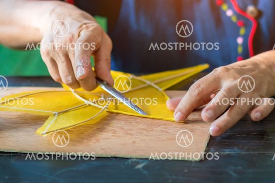 Eldery woman making and build star-shaped kite or thai...