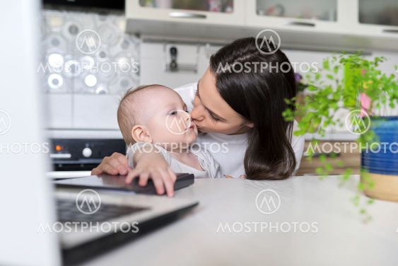 Portrait of mom and baby son sitting at home in kitchen,...
