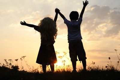 Silhouette, group of happy children playing on meadow,...