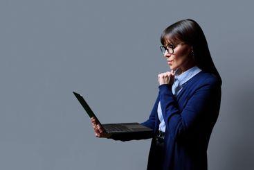 Middle aged business woman using laptop on grey background