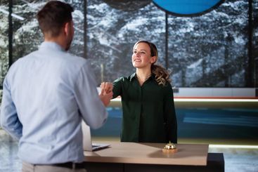 Man At Hotel Talking To Receptionist Woman