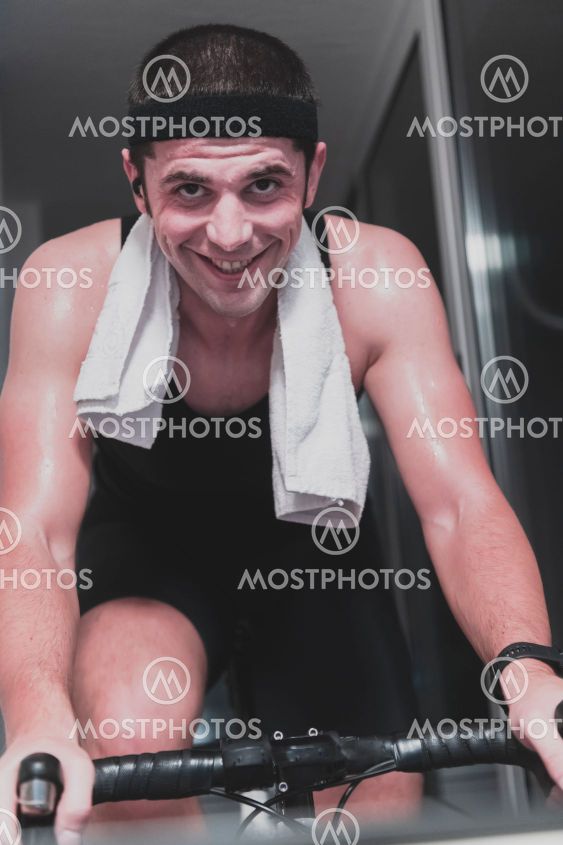 Man cycling on the machine trainer he is exercising in...
