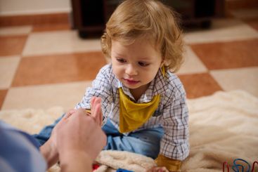Child Playing Indoors on Tiled Floor with a Yellow Bib