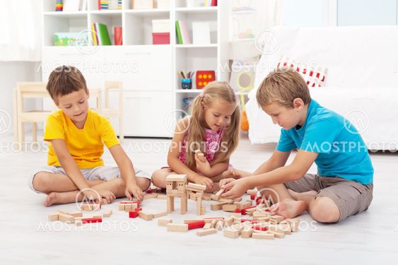 Three kids playing with wooden blocks