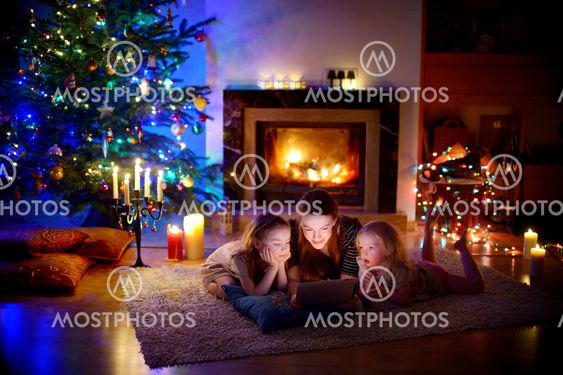 Mother and daughters using a tablet by a fireplace on...