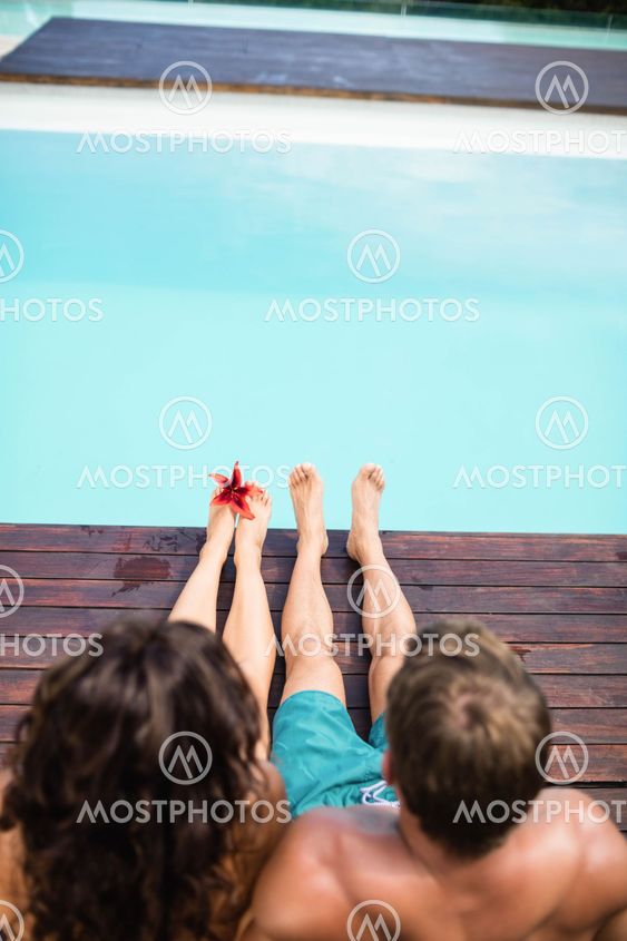 Young couple sitting by poolside