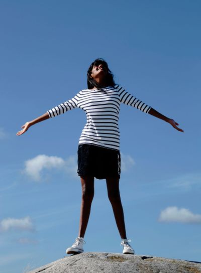 poserar vänd mot himmel och hav