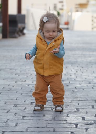 Walking baby girl 1 year old playing in the yard outdoors