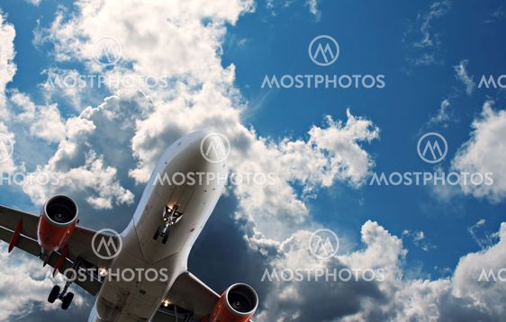Passager jet mod en blå himmel med hvid fluffy skyer