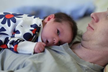 Curious newborn baby lying on father's chest. Childhood,...