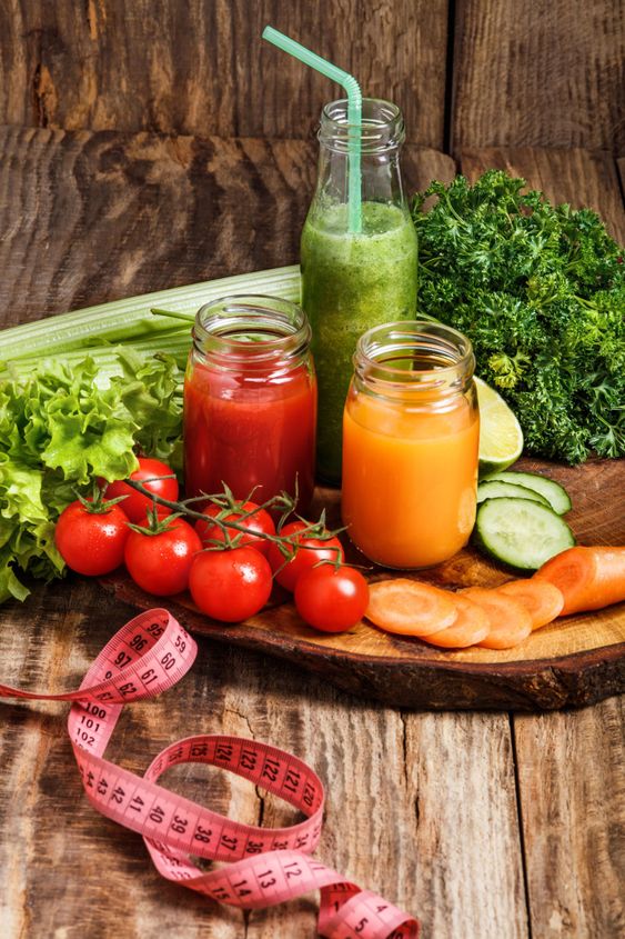 The bottles with fresh vegetable juices on wooden table
