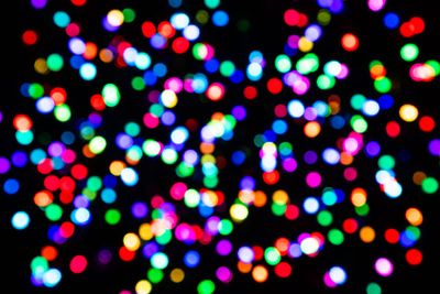 Defocused multicoloured light confetti on a black...