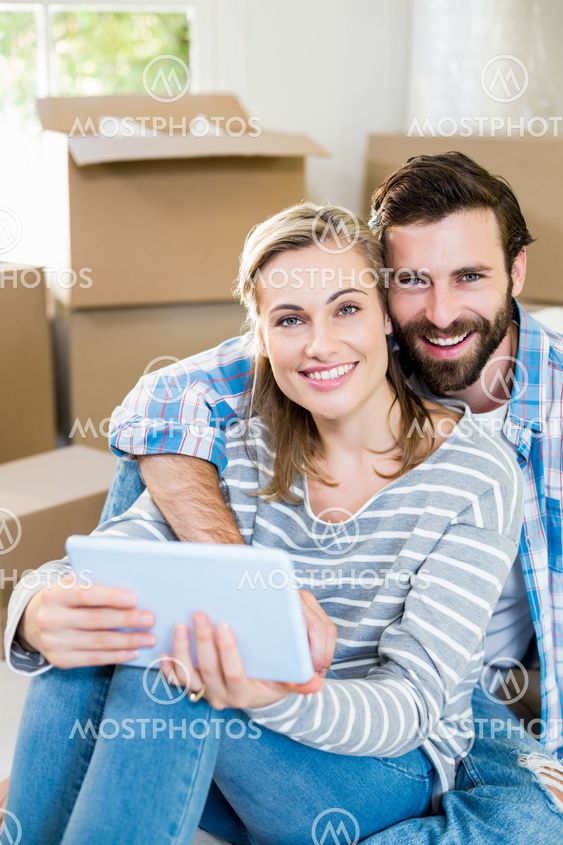 Portrait of couple sitting on floor with digital tablet