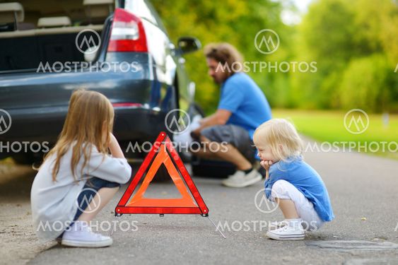 Happy family changing a car wheel