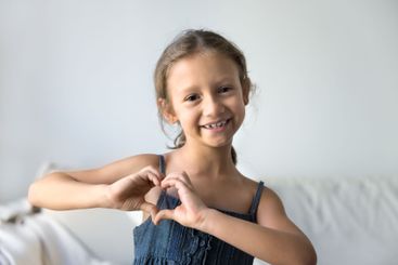 Headshot portrait of cute little girl showing symbol of...