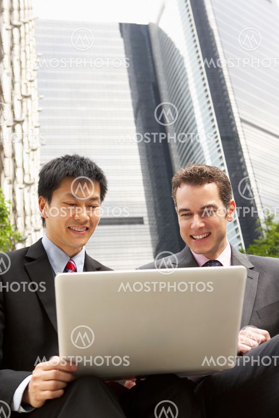 Portrait Of Two Businessmen Working On Laptop Outside Office