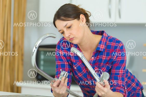 woman is trying to repair a water tap