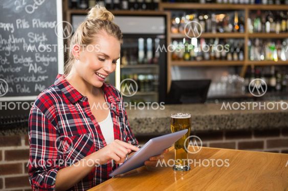 Pretty woman having a beer and looking at tablet