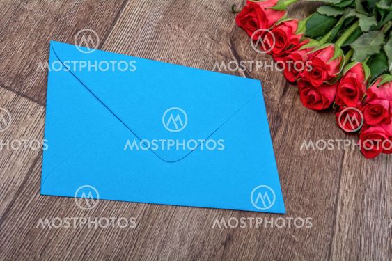 Blue envelope and roses on a wooden background