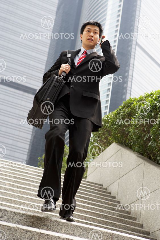 Chinese Businessman Rushing Down Steps On Mobile Phone