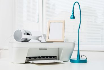 Home office setup featuring a printer, lamp, headphones,...