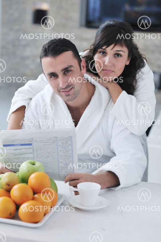 Happy couple reading the newspaper in the kitchen at breakfast