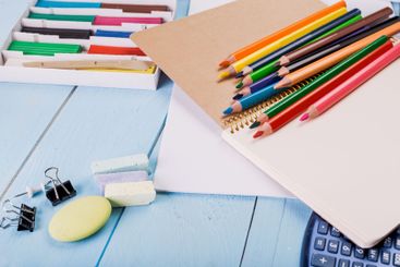 Colorful art supplies arranged on a blue table with a...