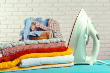 Iron on ironing board on light home interior background