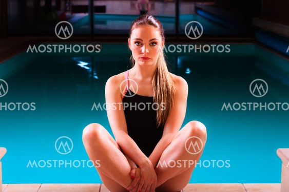 Sporty fit woman at swimming pool edge poolside.