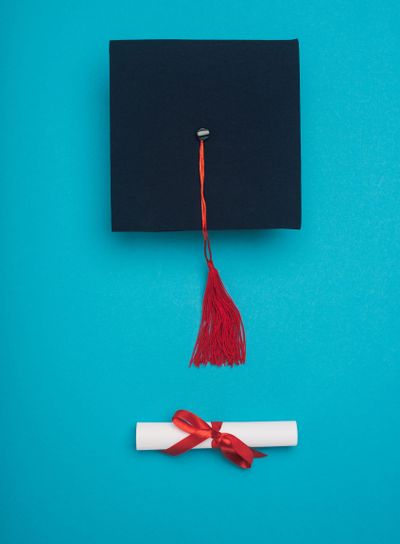 Top view of graduation cap with red tassel and diploma...
