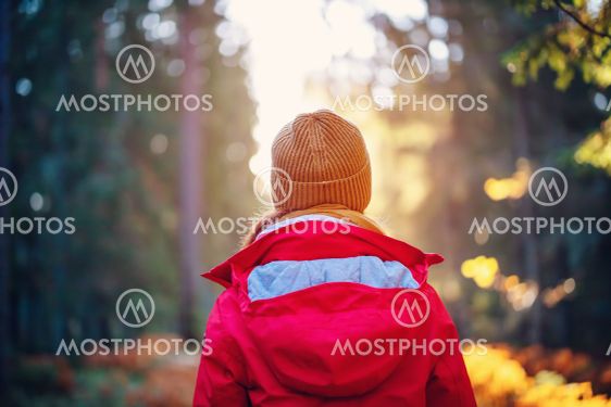 Young woman alone in the autumnal forest in sunrise.