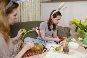 Mother And Daughter Decorating Easter Basket Together.