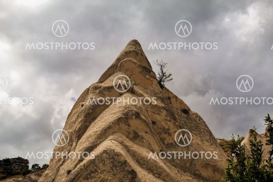 A strange spiky conical rock against a cloudy sky.