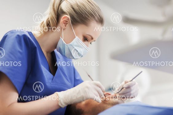 female dentist checking up male patient teeth