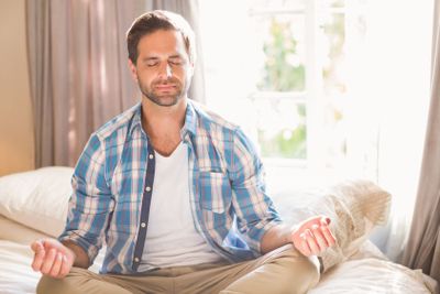 Handsome man doing yoga on his bed