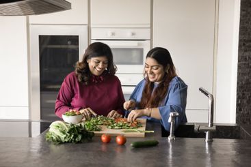 Two women preparing fresh vegetables together in modern...