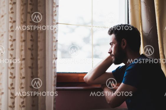Young sad mad sitting by the window