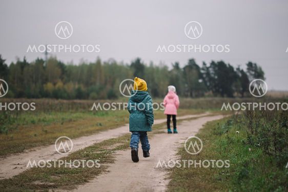 Children play in the field running from flying drone