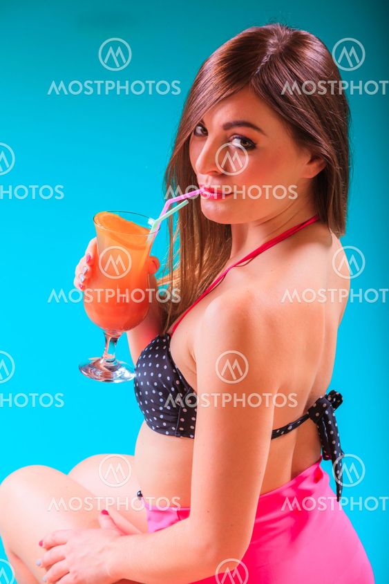 Woman with cocktail drink at swimming pool edge.