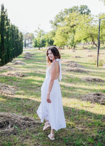 Beautiful woman in white summer dress walking in park